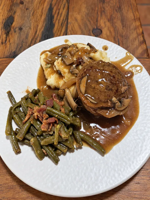 Gravy-covered main with mashed potatoes and green beans prepared by Lino Cantú